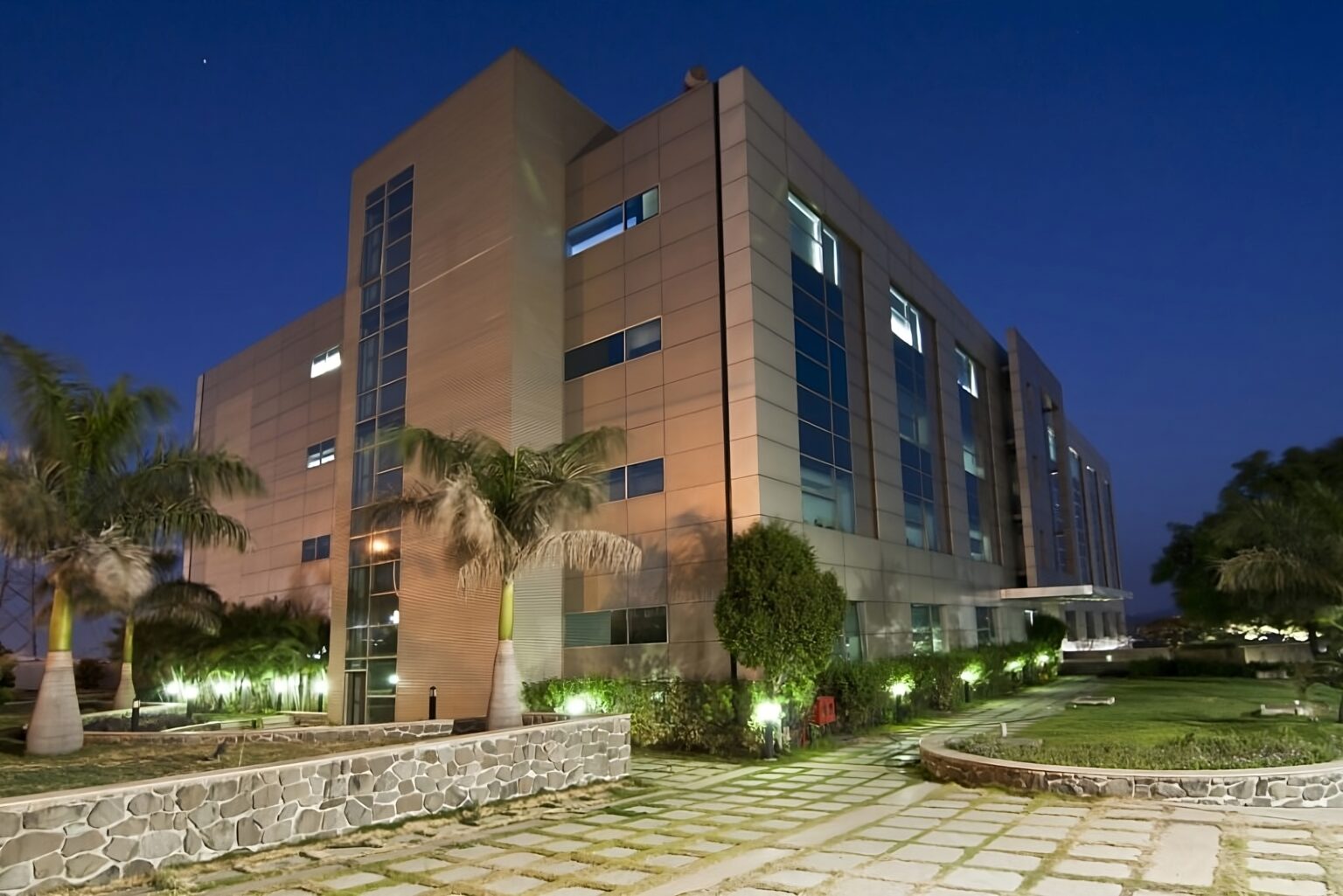 Modern building exterior photographed at blue hour with landscape lighting